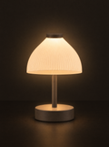 Cloche table lamp: a ribbed dome shade glowing above a slim stem and round base