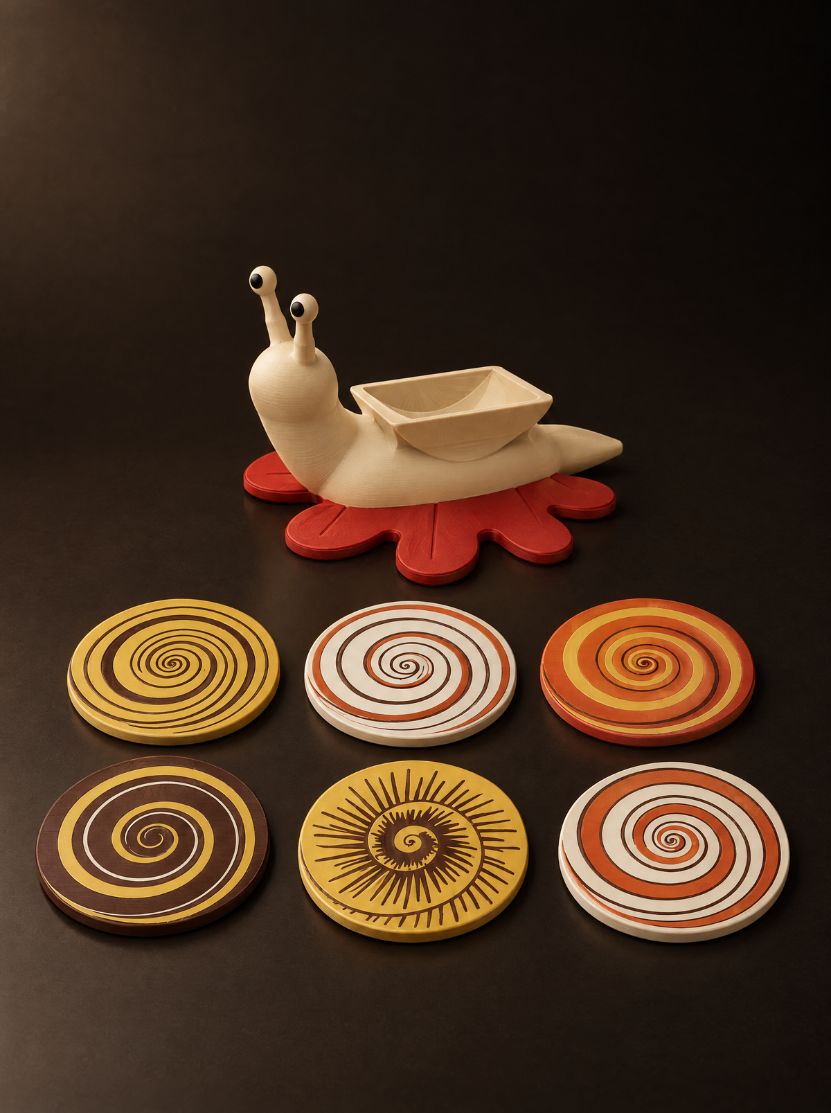 Snail Shell holder with an empty cradle and its six spiral coasters laid out in gold, cream, rust and brown